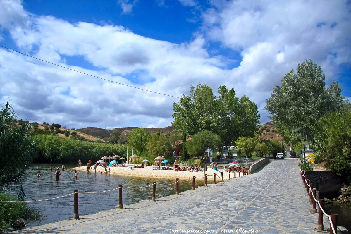 The sandy bathing area, river water and stone walkway at Pego Fundo river beach in Alcoutim