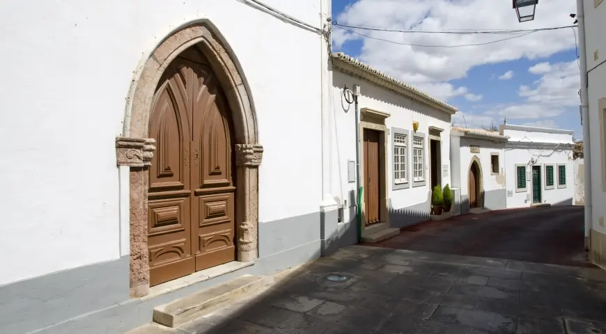 The stone-framed chapel door beside a narrow old-town street in Albufeira