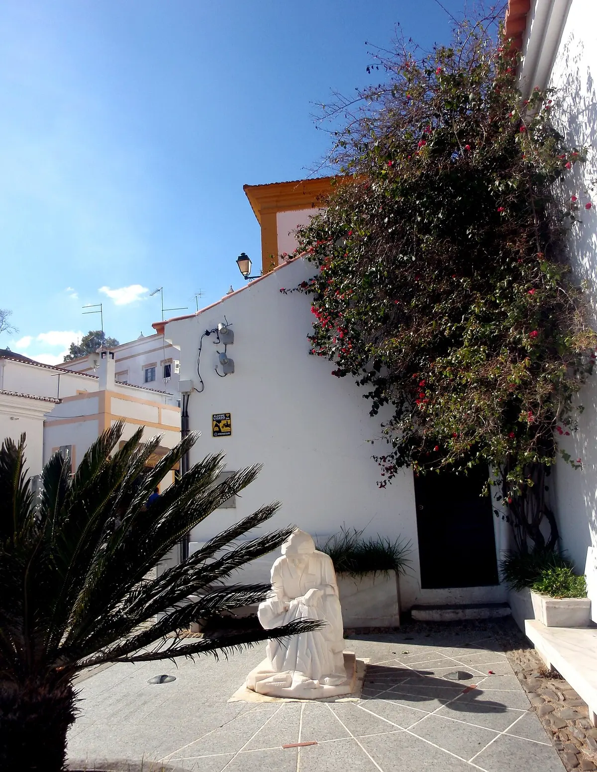 Side of Santo António chapel above a garden and stone statue in Alcoutim