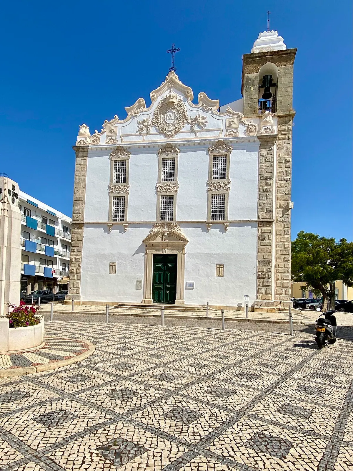 Twin-towered parish church behind patterned paving in Olhão