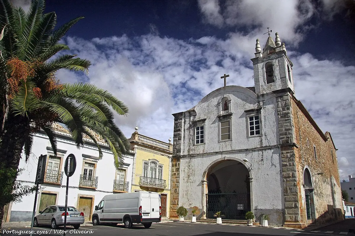 Façade and central bell tower of Igreja de São Paulo beside a square in Tavira