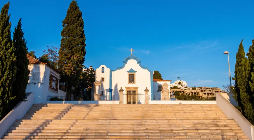 The Orada chapel beyond its broad steps and trees near Albufeira Marina