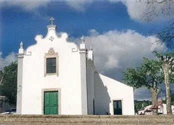 The small white São Luís chapel in Alte, with a green door and decorative gable