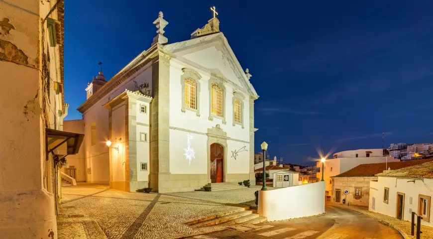 Albufeira parish church illuminated above a sloping old-town street