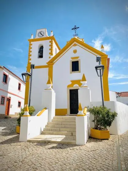 Guia parish church with its yellow trim, clock tower and entrance steps