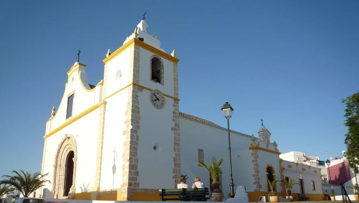 The white and yellow façade and bell tower of Alvor’s main church
