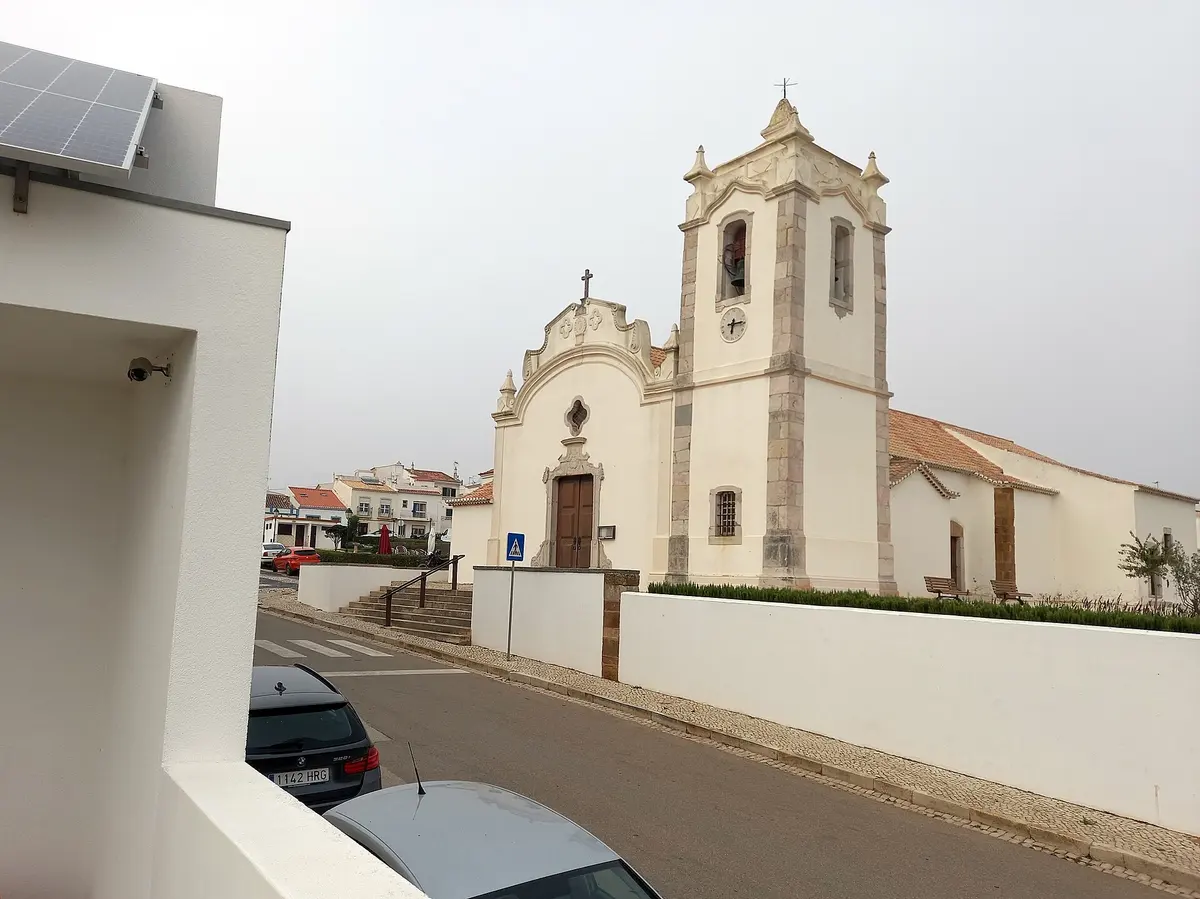 The white parish church and bell tower beside the street in Vila do Bispo