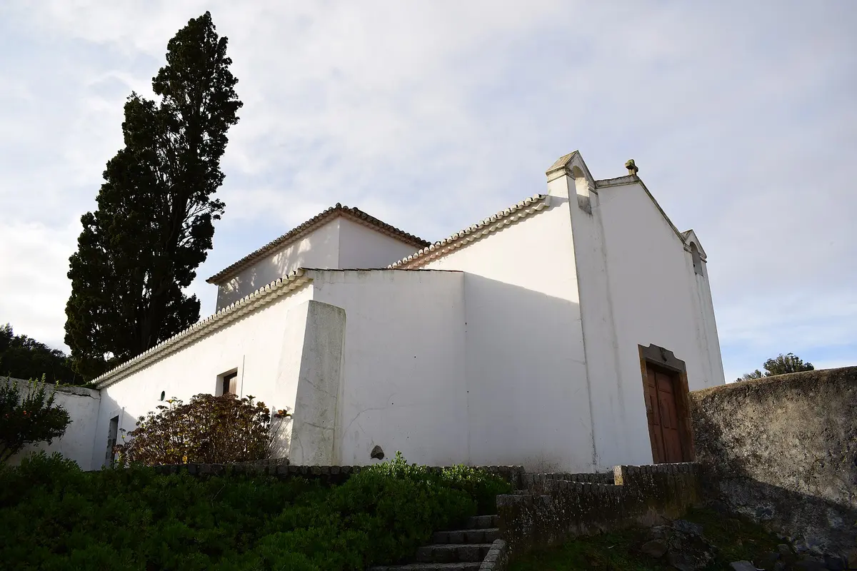 The modest white São Sebastião chapel beside a tall tree in Monchique