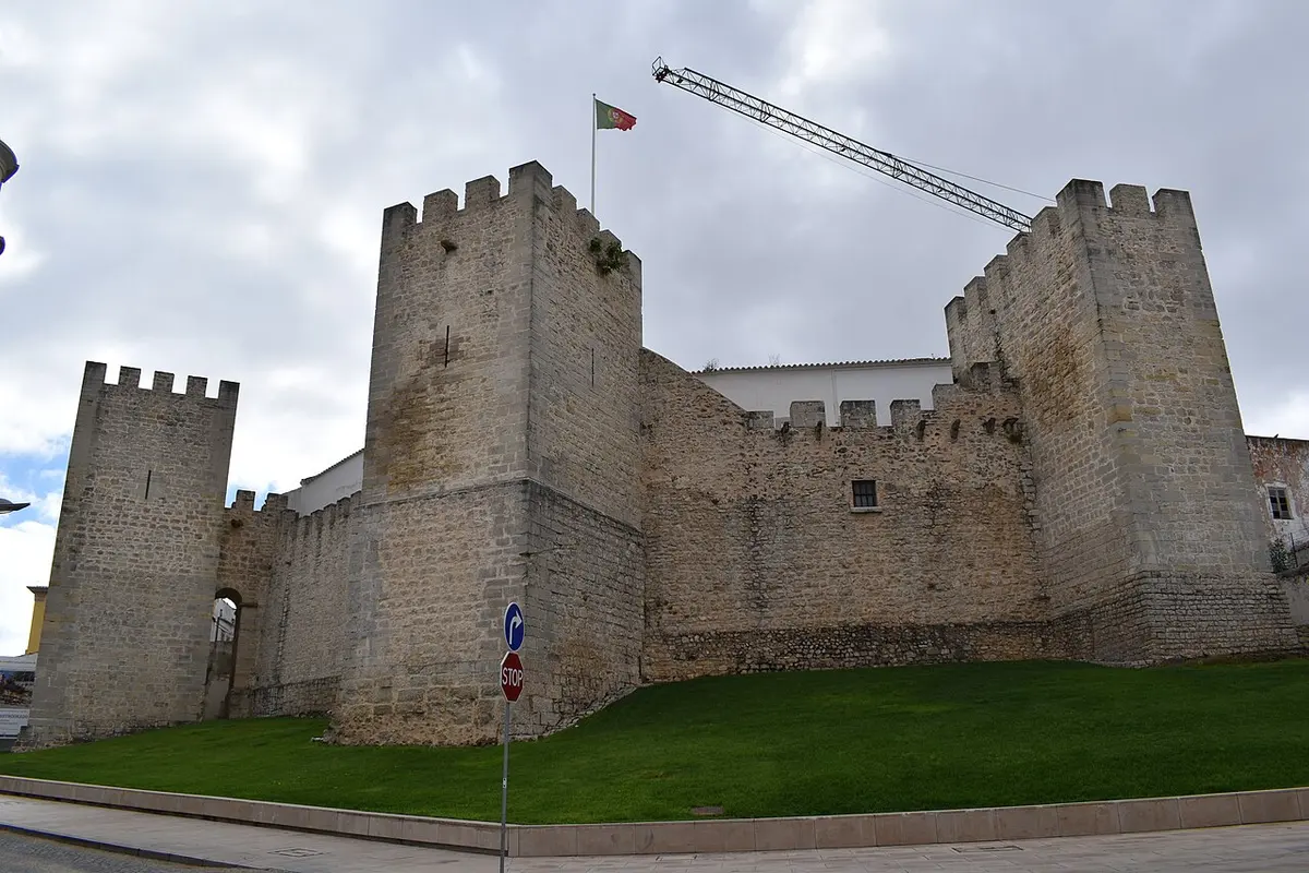 Stone towers and walls of Loulé Castle beside a lawn