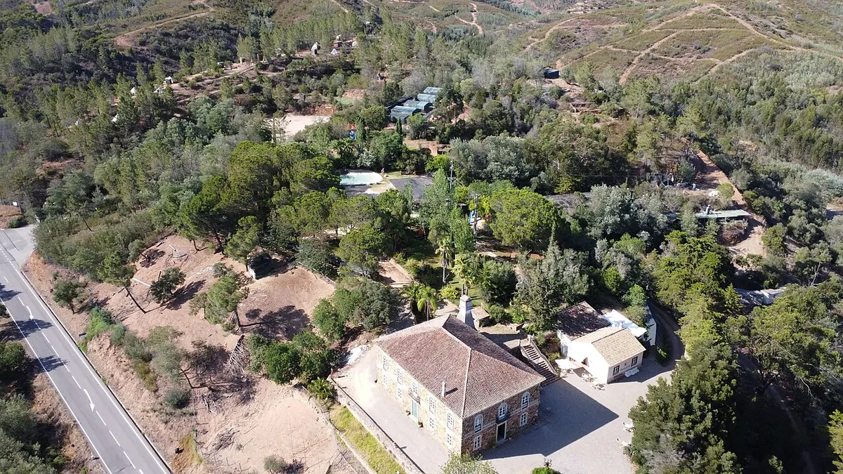 Aerial view of the stone manor house, wooded grounds and paths at Parque da Mina