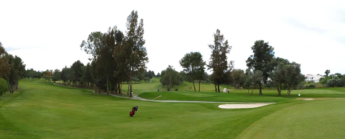 Tree-lined fairway, bunker and golf bag at Alto Golf in Alvor