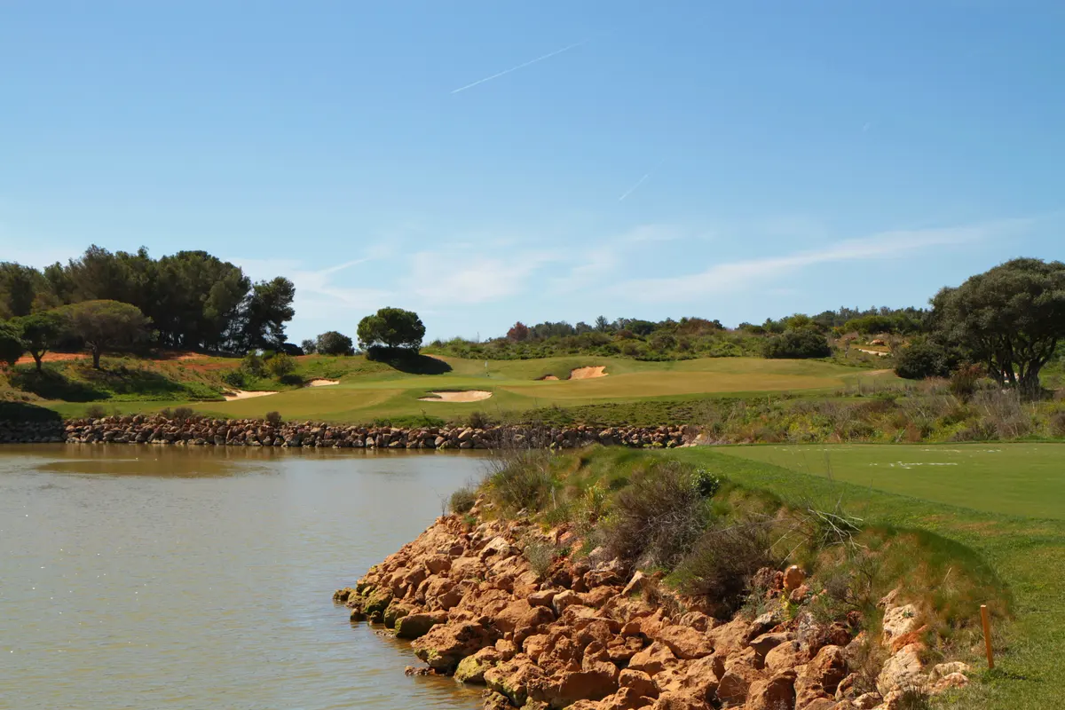 Lake edged with rocks below the green and bunkers at Palmares Golf