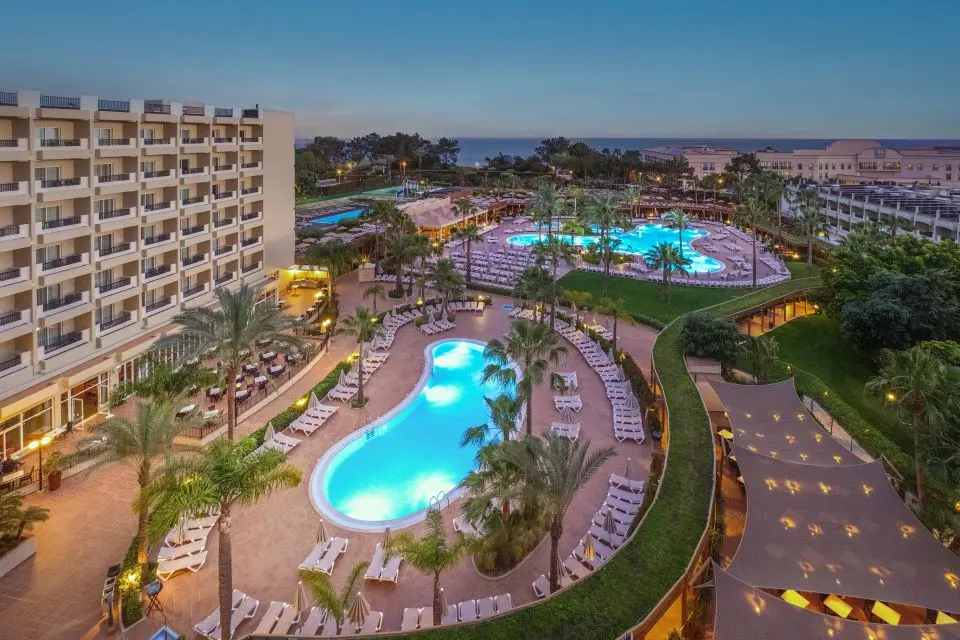 The outdoor pools and hotel buildings at 3HB Guaraná illuminated at dusk