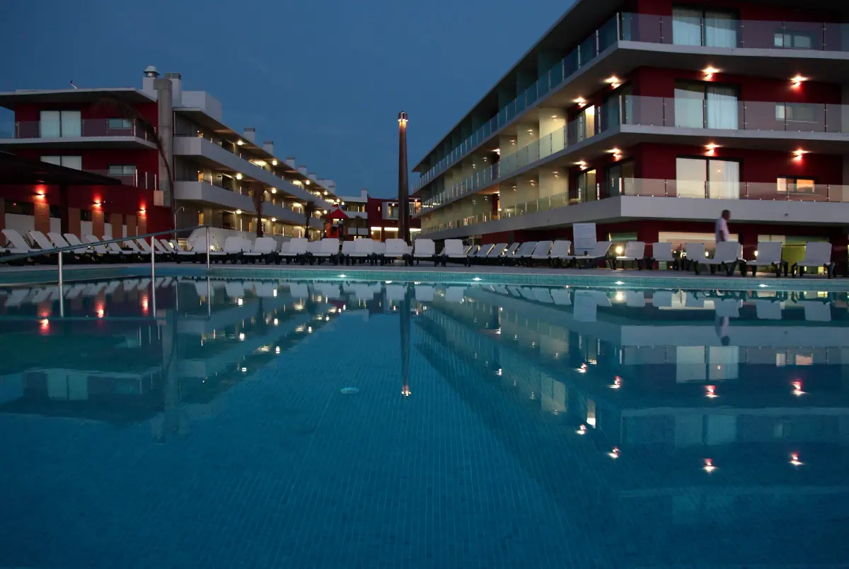 The pool and contemporary hotel buildings at Água Hotels Riverside illuminated at dusk