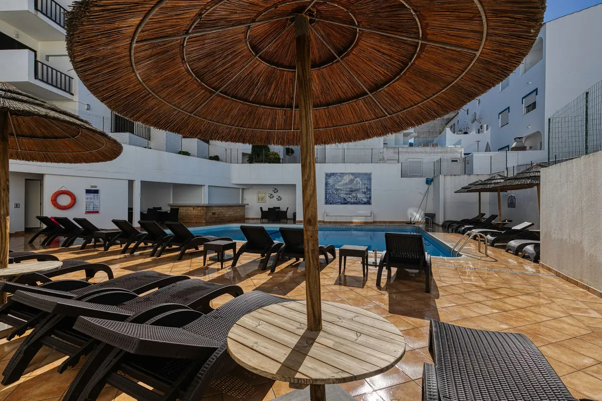 Parasols and sun loungers around Hotel Carvoeiro Plaza’s courtyard pool