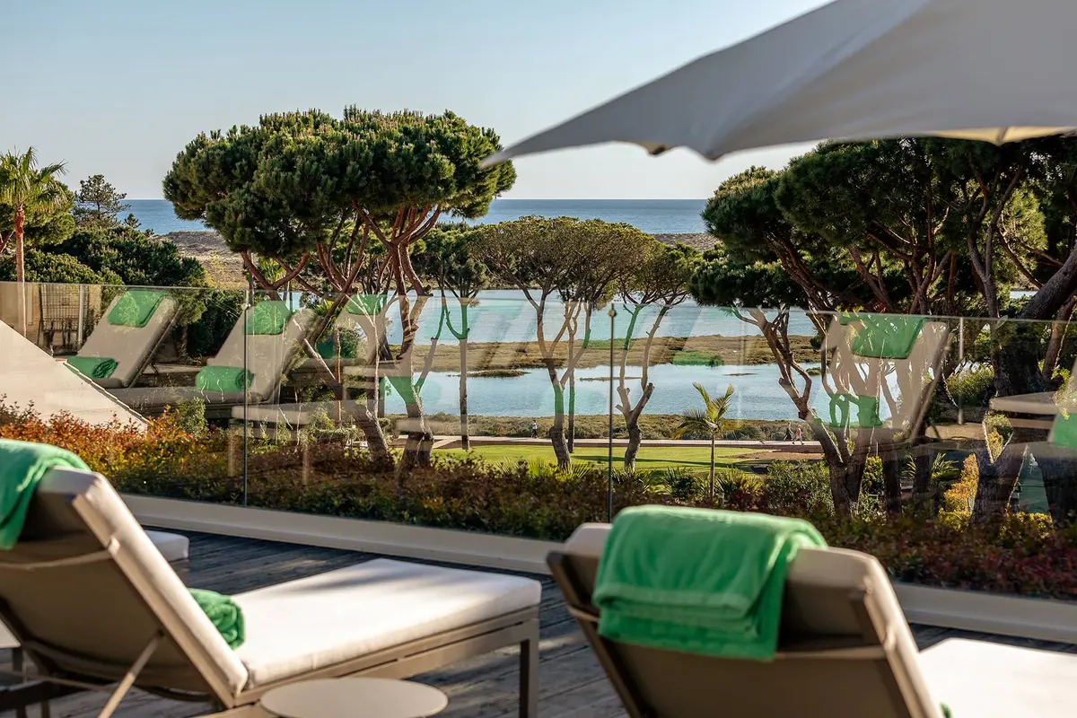 A shaded lounge terrace overlooking the pool and estuary-side landscape at Hotel Quinta do Lago