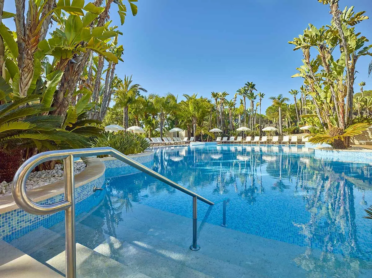 Palm trees and tropical gardens around a pool at Ria Park Hotel & Spa