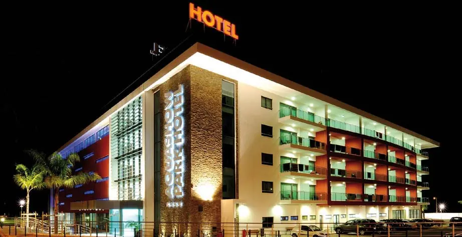The illuminated Aquashow Park Hotel building at night, with its hotel sign above the entrance corner