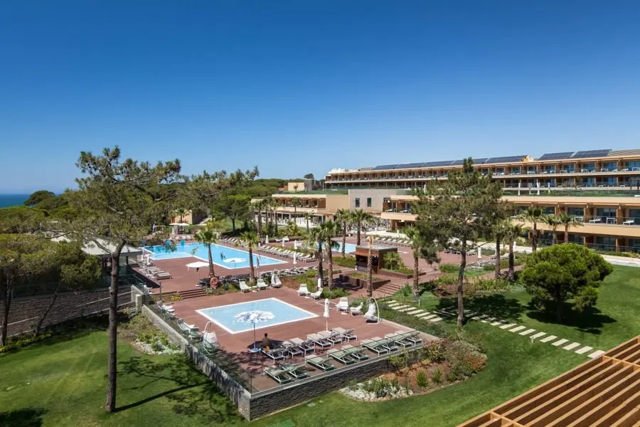 EPIC SANA Algarve guest-room buildings above landscaped gardens, palm trees and outdoor pools