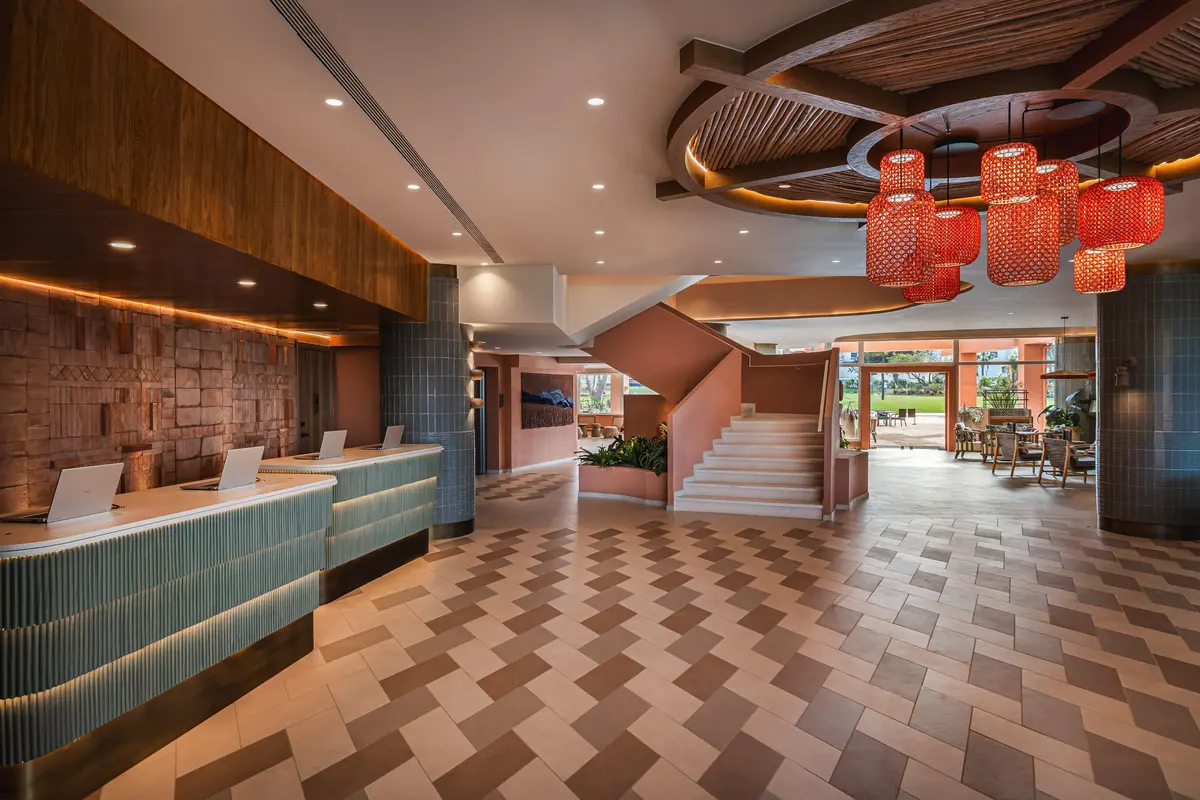 The new Hyatt Regency Vilamoura lobby with a patterned floor, timber reception desk and red pendant lamps