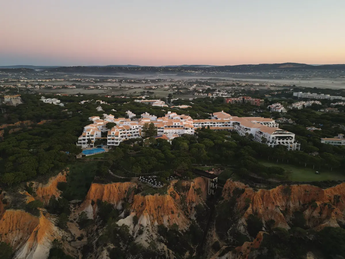 Pine Cliffs Resort hotel buildings above the red coastal cliffs near Olhos de Água