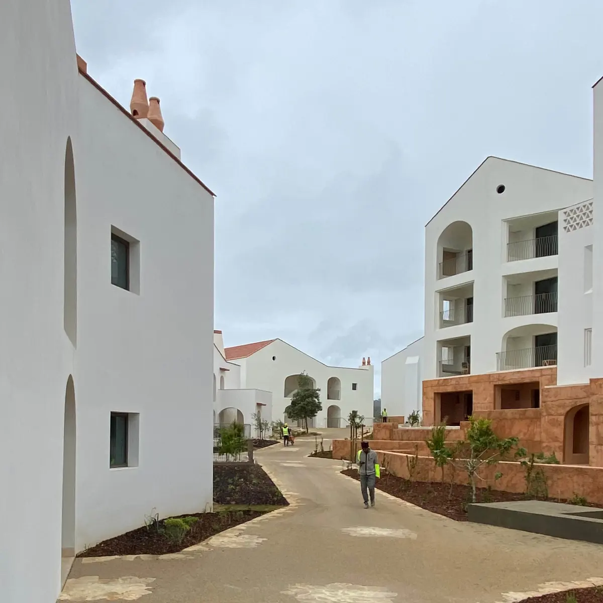White hotel buildings, terracotta paving and balconies along a pedestrian lane at Viceroy at Ombria Algarve