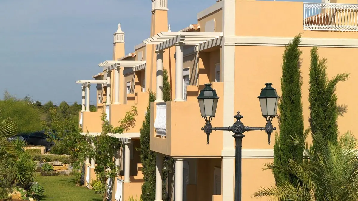 Golden ochre resort buildings, white pergolas and landscaped gardens at Vila Alba Resort