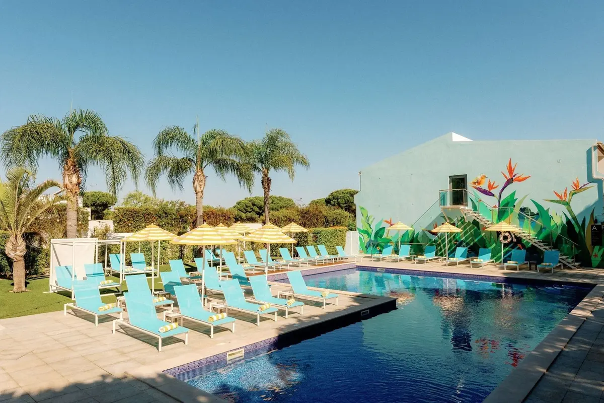 The Magnolia Hotel’s outdoor pool with turquoise loungers and palm trees