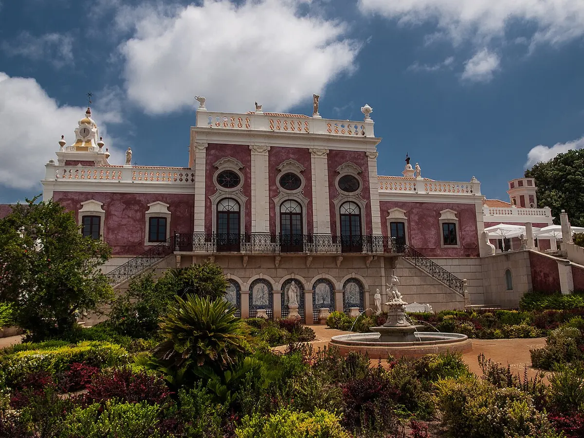 Pink palace façade above formal gardens at Pousada Palácio Estoi