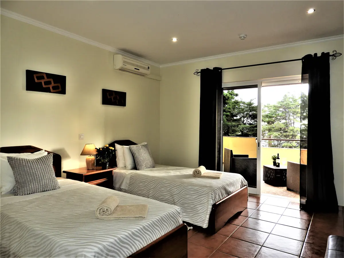 Twin beds and a terrace doorway in a room at Rocha da Gralheira hotel