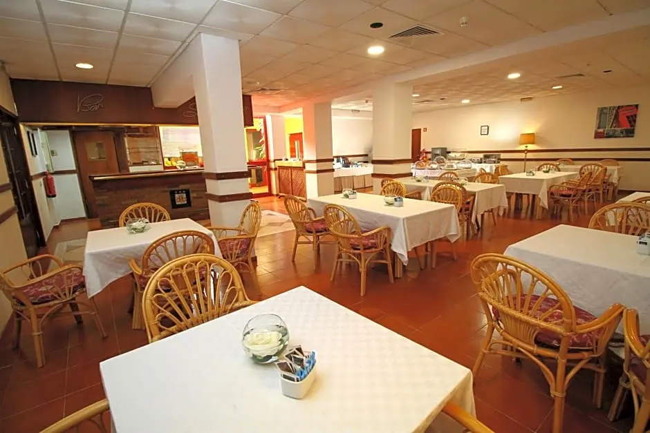 The breakfast room at Hotel Dom Bernardo with white tablecloths, wooden chairs and a tiled floor