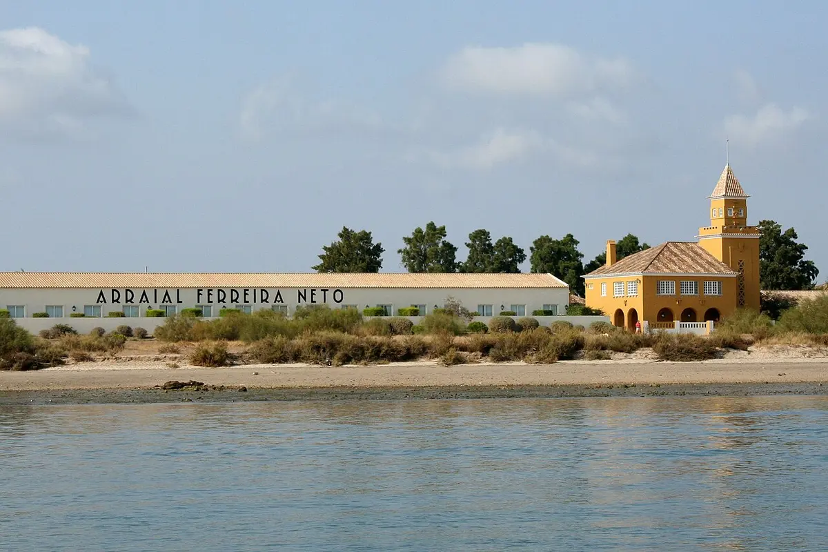 The white Arraial Ferreira Neto wing and yellow tower of Vila Galé Albacora beside the lagoon