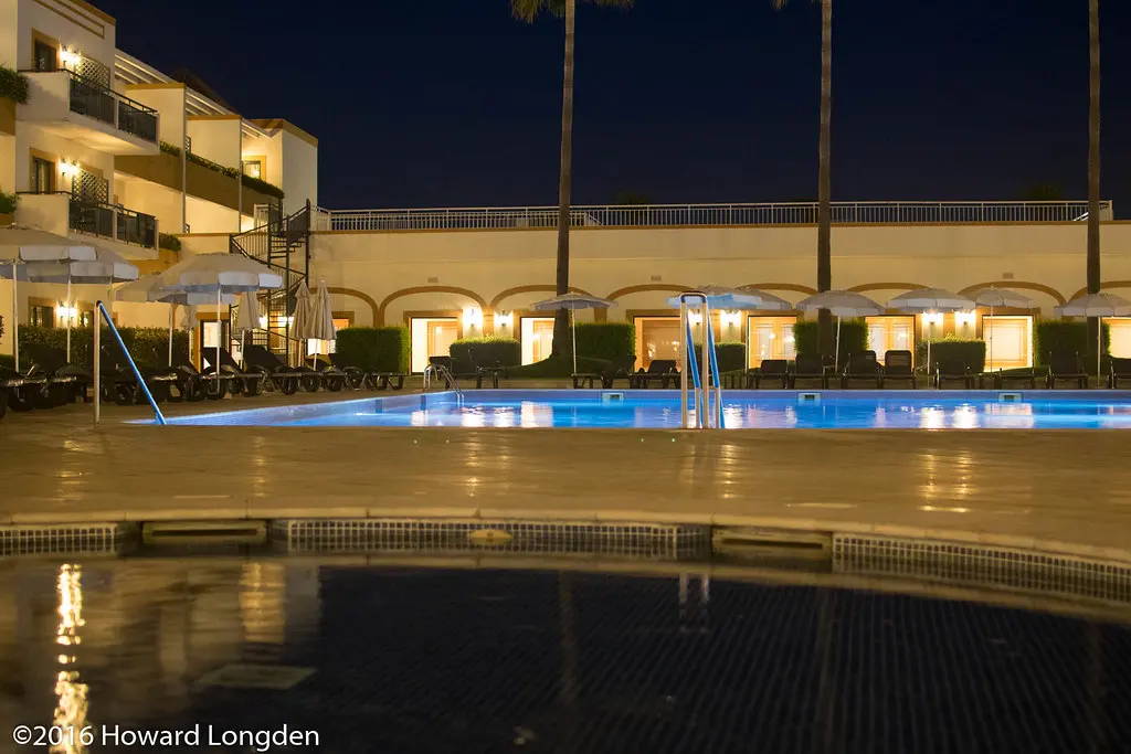 The courtyard swimming pool and softly lit hotel balconies at Vila Galé Tavira after dark
