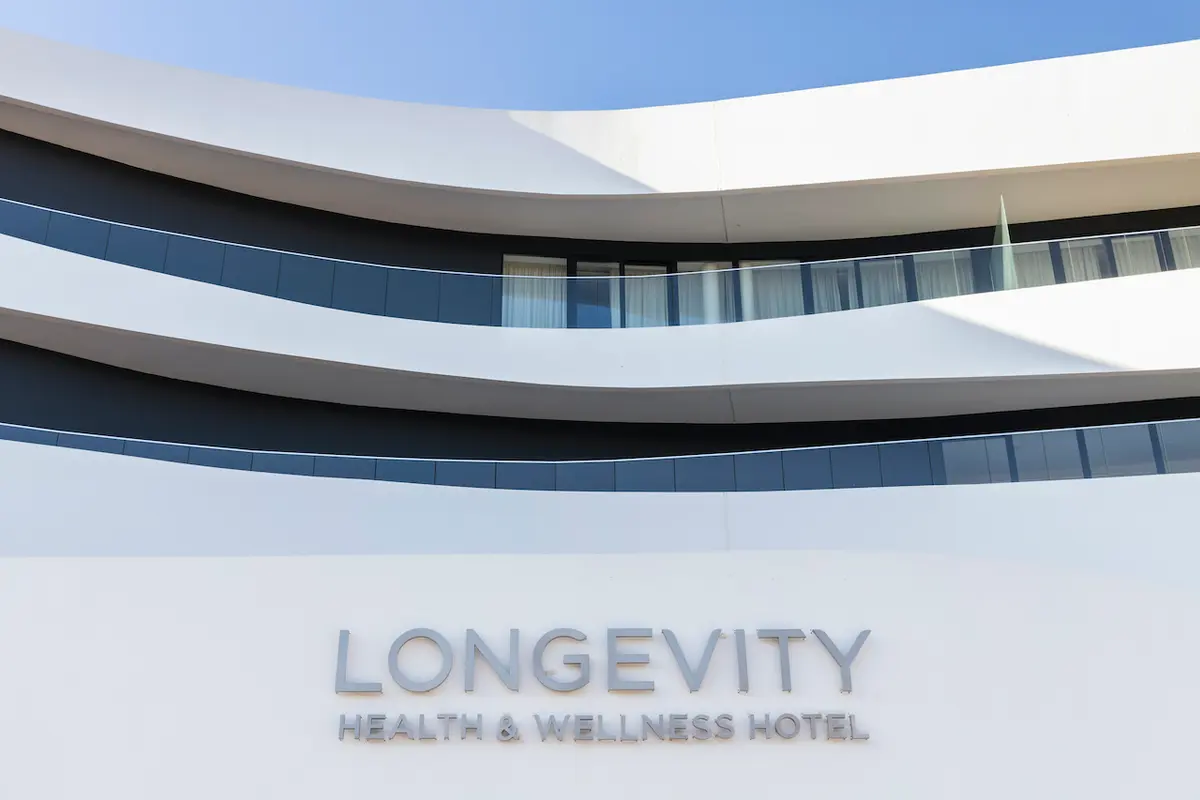 Curved white balconies and the hotel name on the facade of Longevity Health & Wellness Hotel