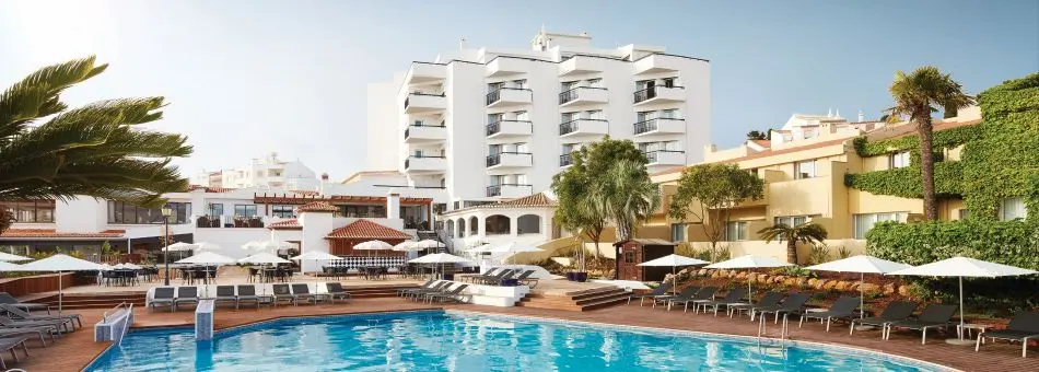 The outdoor swimming pool and white terraced hotel buildings of NH Lagos Algarve Resort