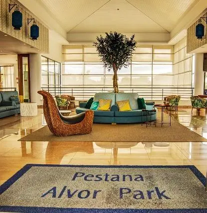 The lobby of Pestana Alvor Park with a central indoor tree and the hotel name on the entrance mat