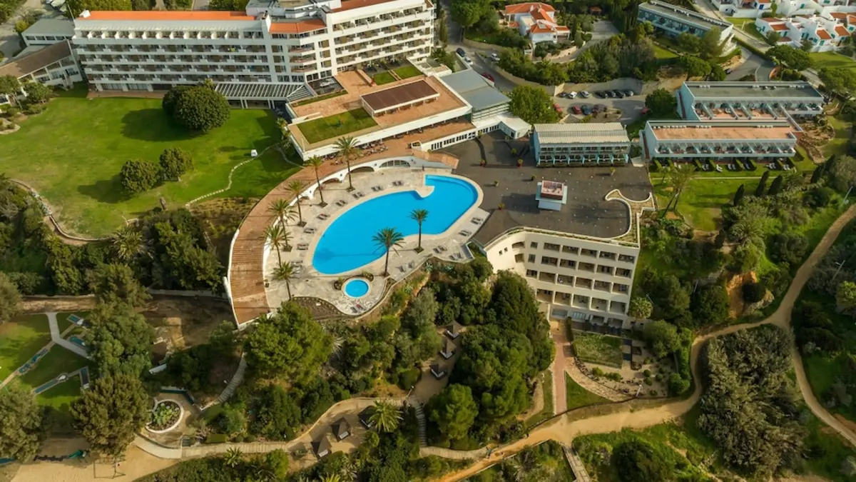 An aerial view of the white Pestana Alvor Praia hotel, curved outdoor pool and landscaped cliff-top grounds
