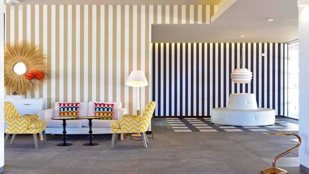 A light reception lounge with striped walls and yellow patterned chairs at Pestana Alvor South Beach