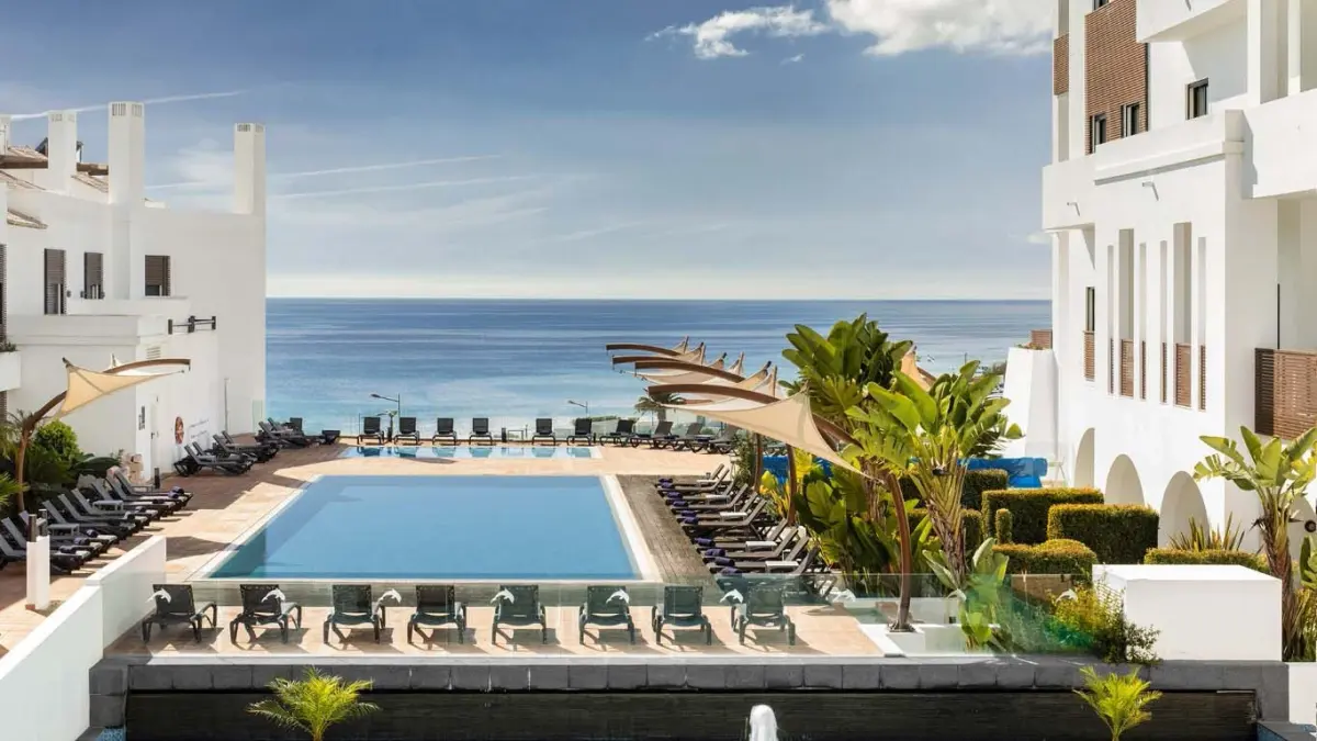 The pool terrace between the hotel buildings at Belmar Spa & Beach Resort, with Porto de Mós and the sea beyond