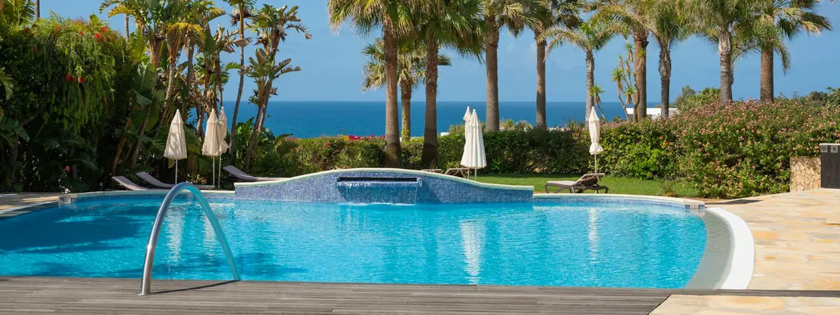 The swimming pool and palm-lined gardens at Vila Luz with the sea beyond
