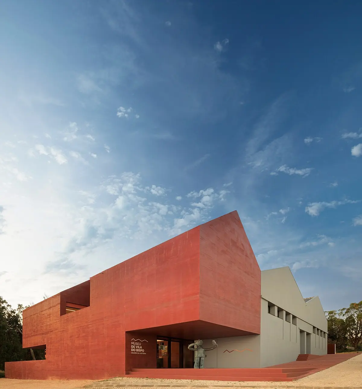 Red projecting entrance and white exterior of Museu de Vila do Bispo