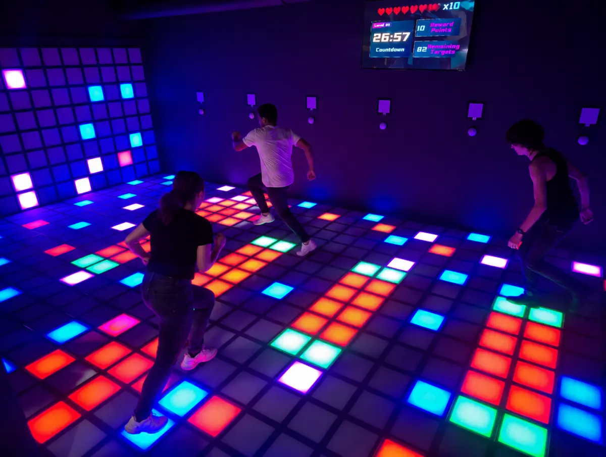 Visitors playing on a colourful illuminated interactive floor at NeoFun Faro