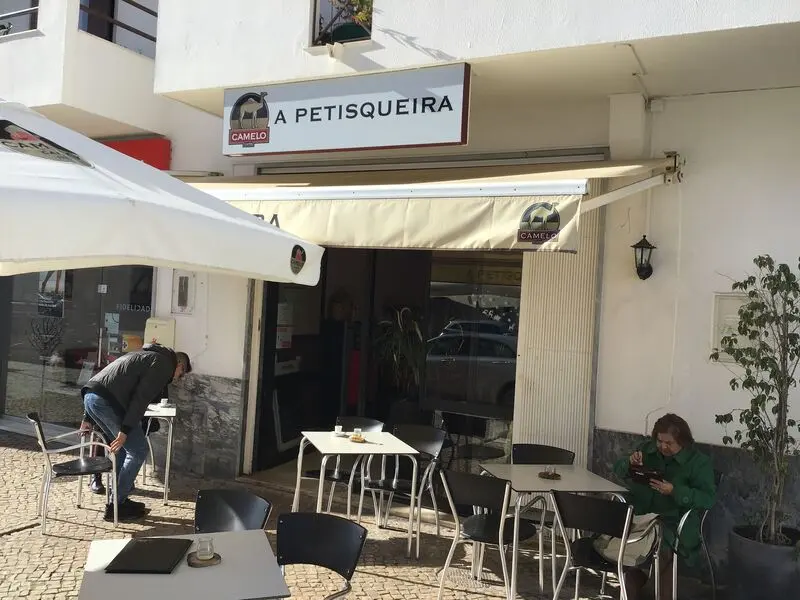 Outdoor tables below A Petisqueira’s sign on Avenida da Liberdade in São Brás.