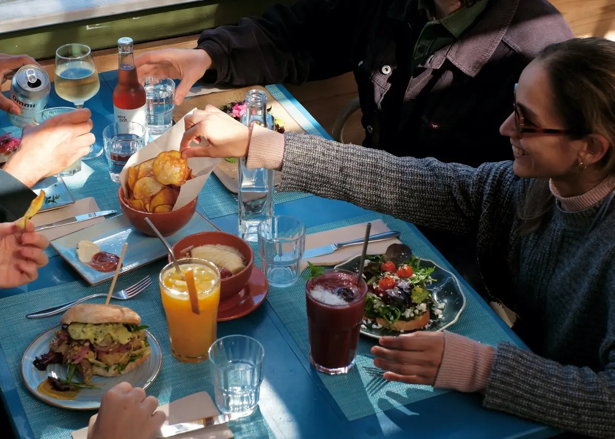 Guests sharing a meal and drinks at a blue table at Assomar
