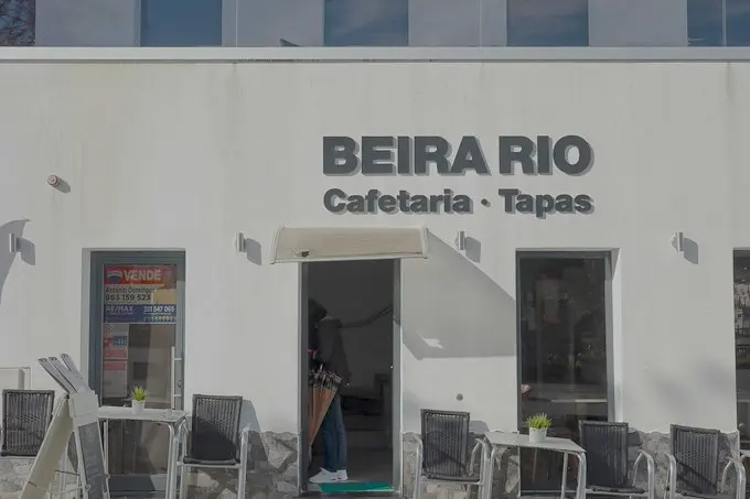 The Beira Rio café and tapas sign above its riverfront entrance and outdoor tables.