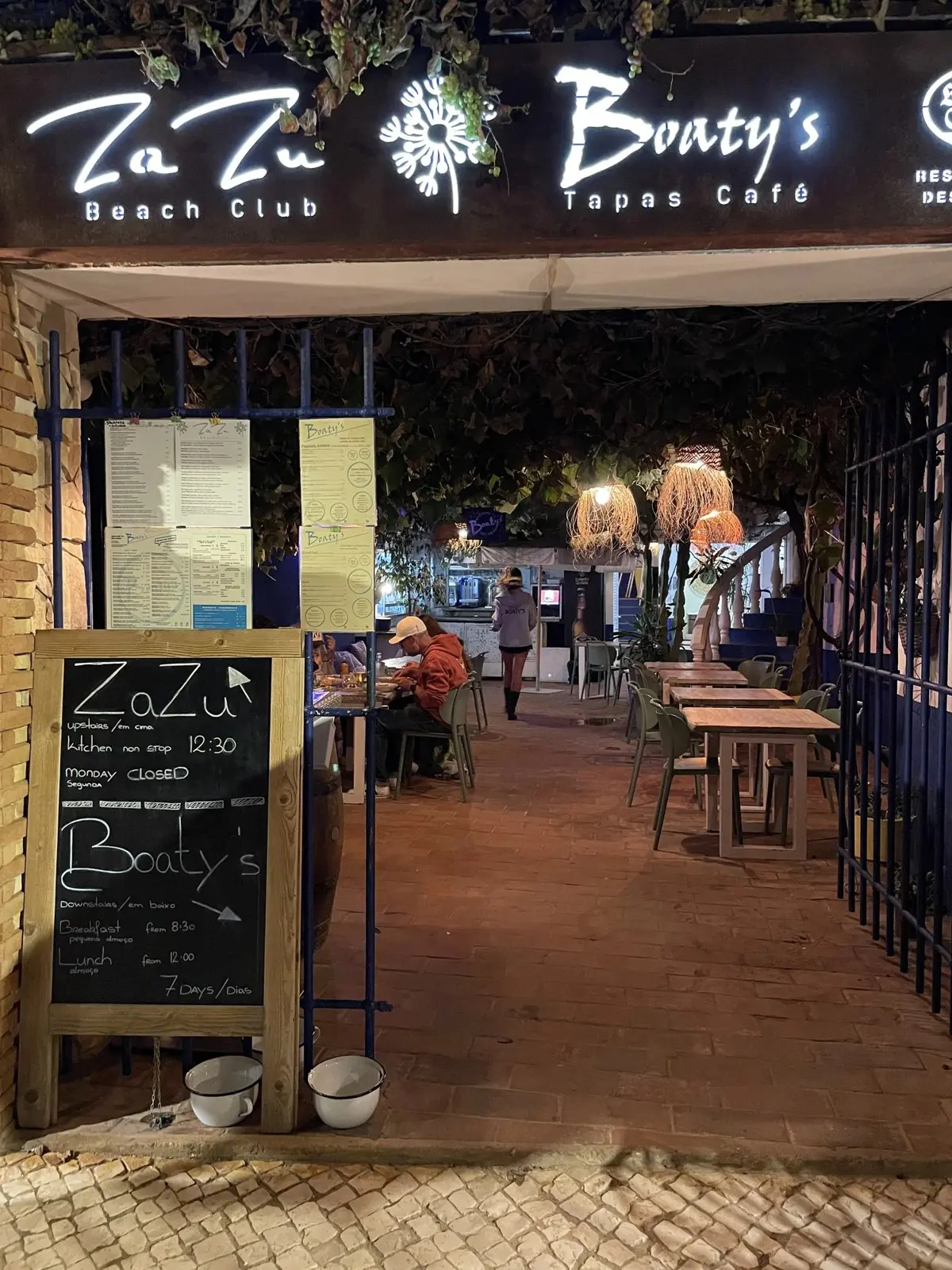 Night-time entrance showing the Boaty’s and ZaZu signs above the garden seating