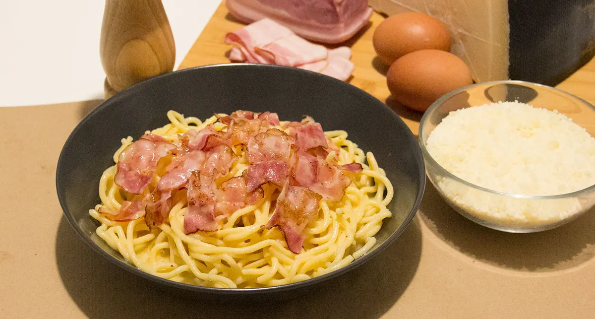 A bowl of carbonara with ingredients arranged behind it, from Botega Italiana’s own food gallery.