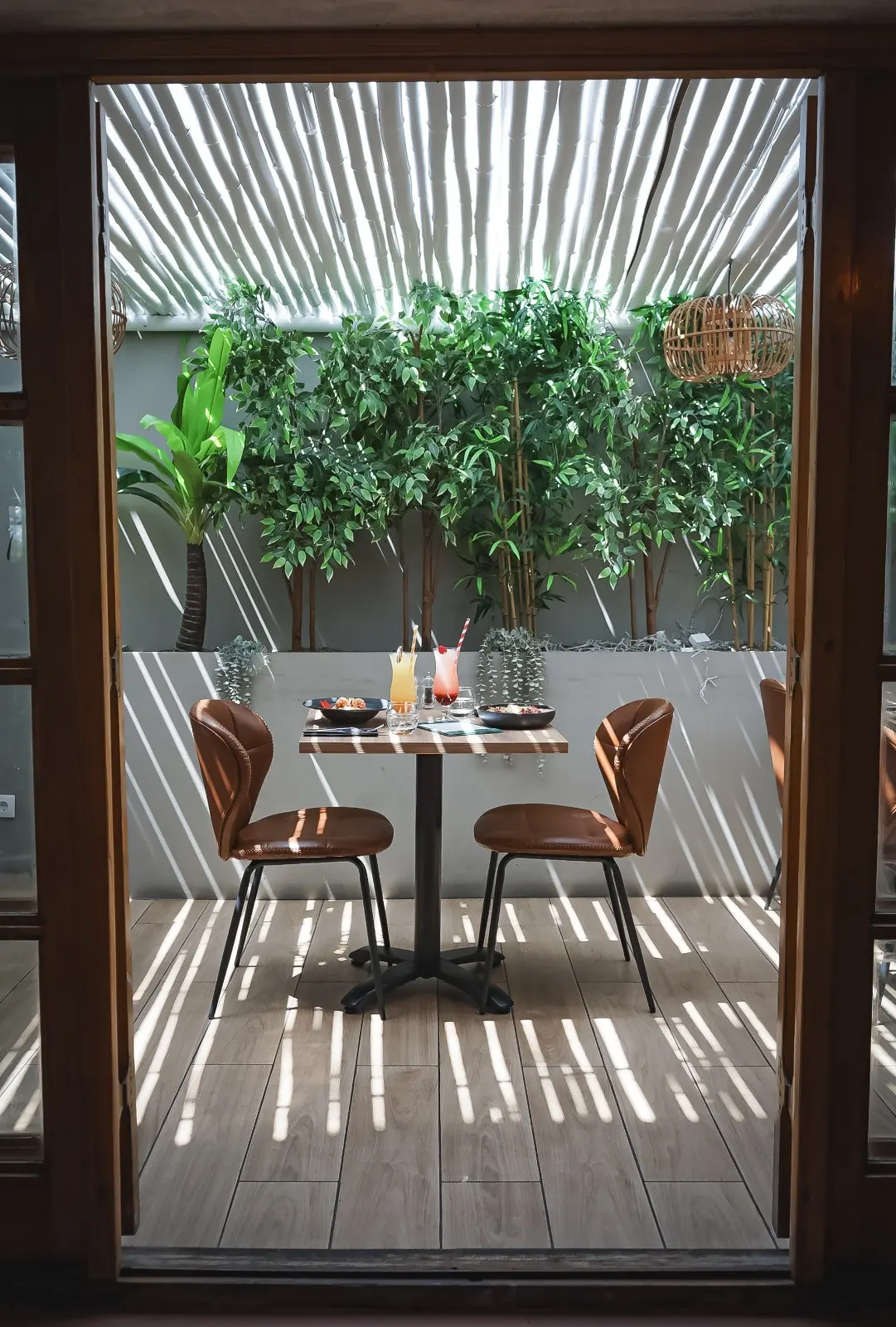 A restaurant table framed by a doorway and greenery at Butchers Almancil