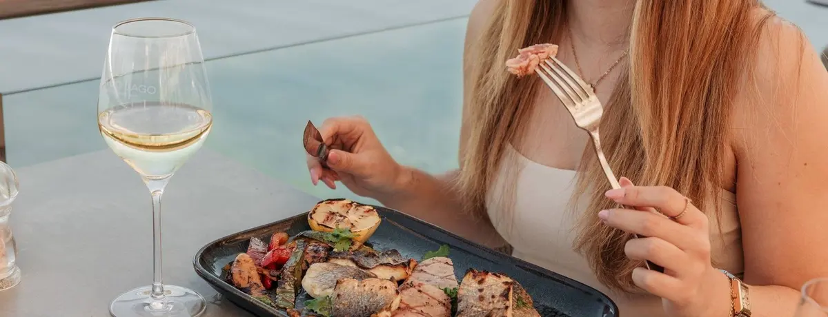 A diner with a plated meal and wine at a waterside table at Casa do Lago