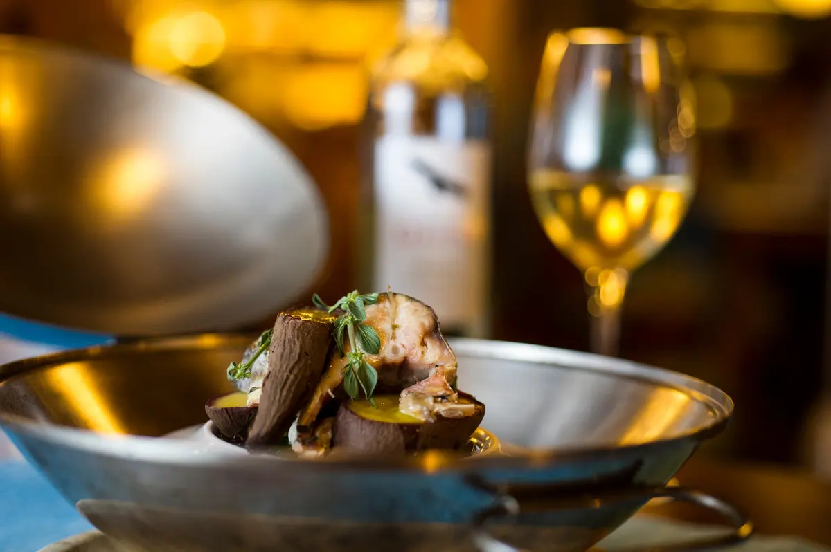 A plated dish and wine photographed inside Chá com Água Salgada, from its official restaurant gallery.